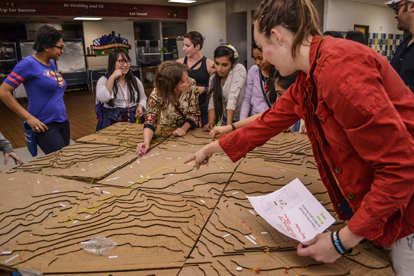 Students discussing a large topographic model during a civil engineering leadership activity