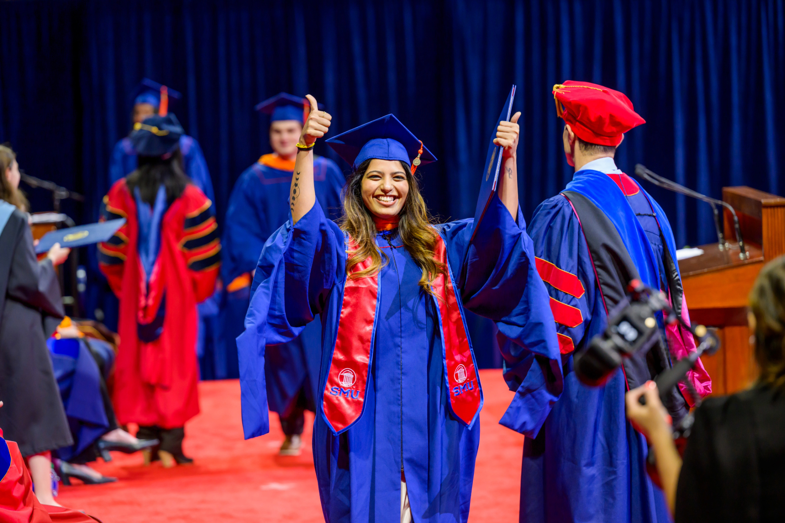 Smiling 色花堂_色花堂 98堂 Lyle Graduate celebrates getting her degree in cap and gown with a thumbs up