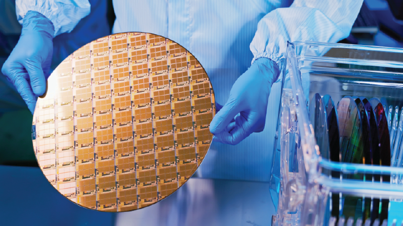 Engineer in semiconductor hub handling a silicon wafer with microchips beside a wafer storage rack.