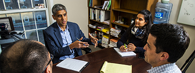 Students sitting around a table listening to an instructor