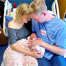 Trevor Thompson and wife in hospital bed with their newborn daughter