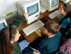 A group of children gathered around a computer, engaged in a reading activity for Istation Indicators of Progress.