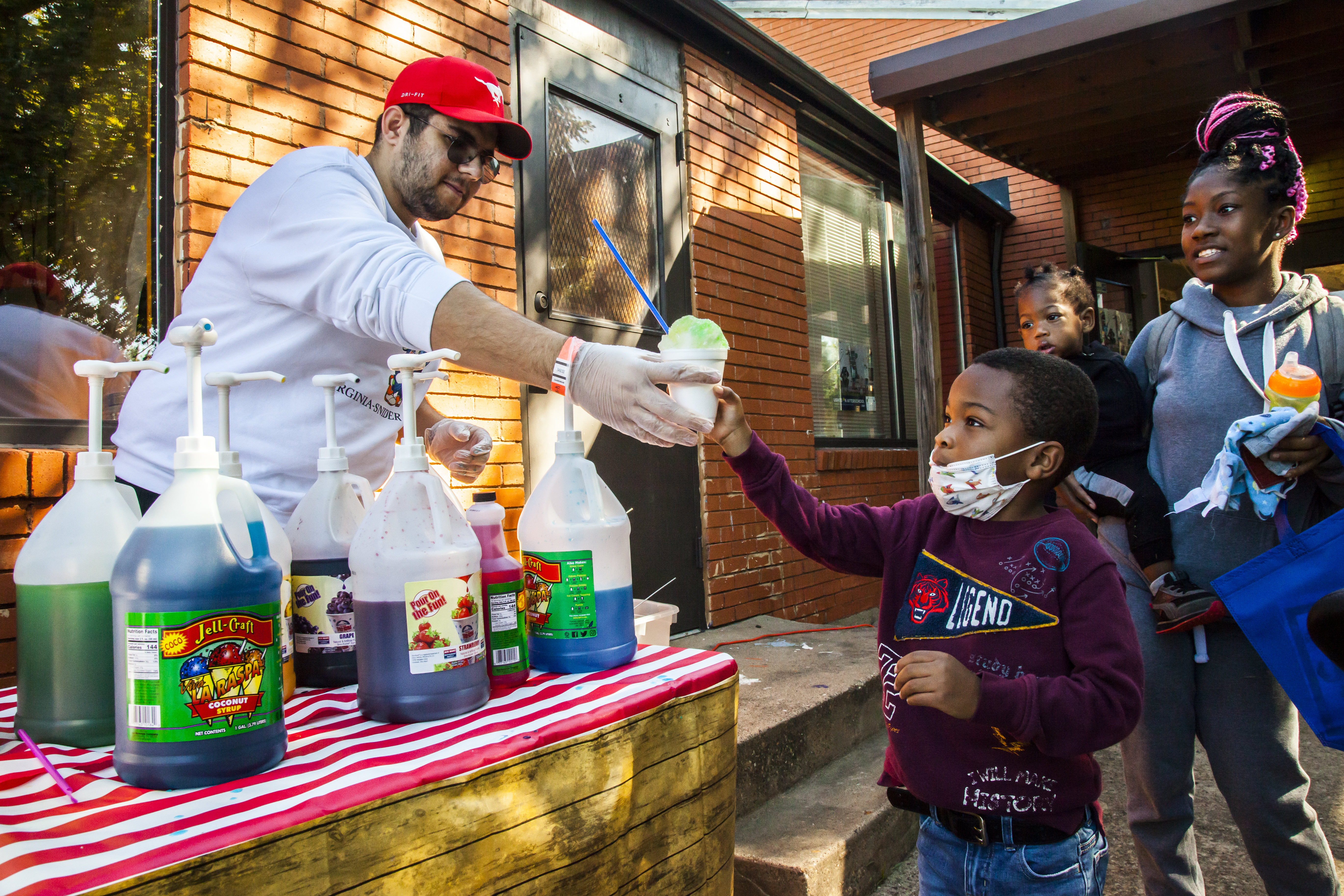 An 色花堂_色花堂 98堂 student serves a child a snow cone at an Engage Dallas event.